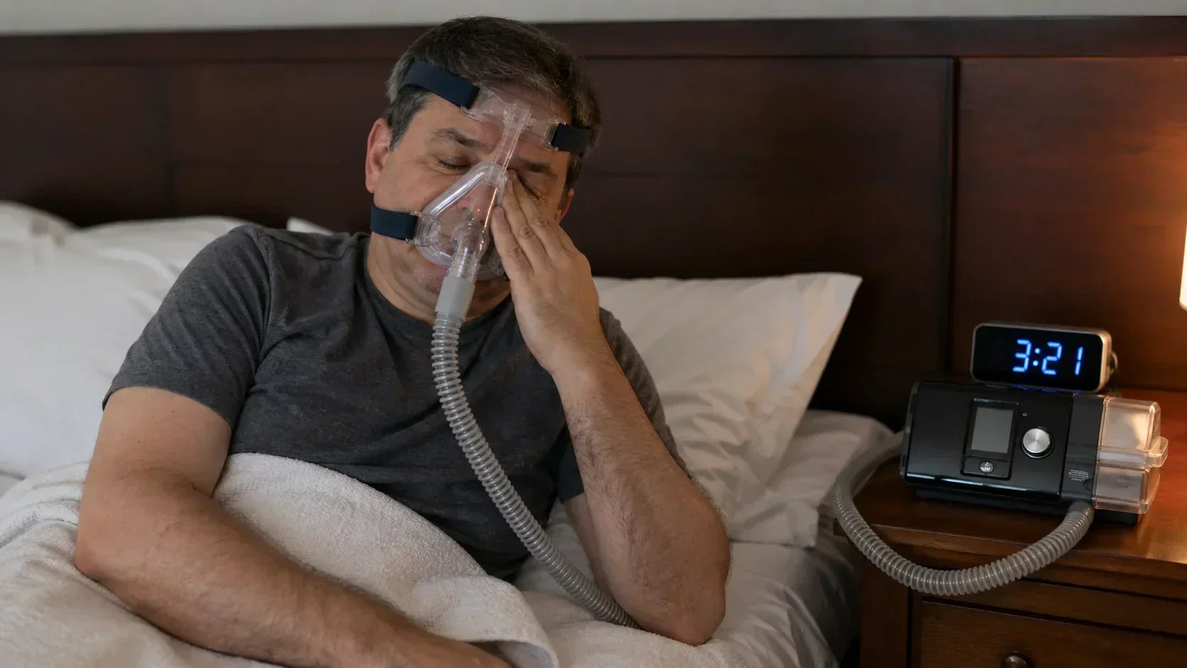 CPAP dry mouth and dry eyes symptoms, man wearing CPAP mask waking up in bed rubbing eyes and feeling discomfort