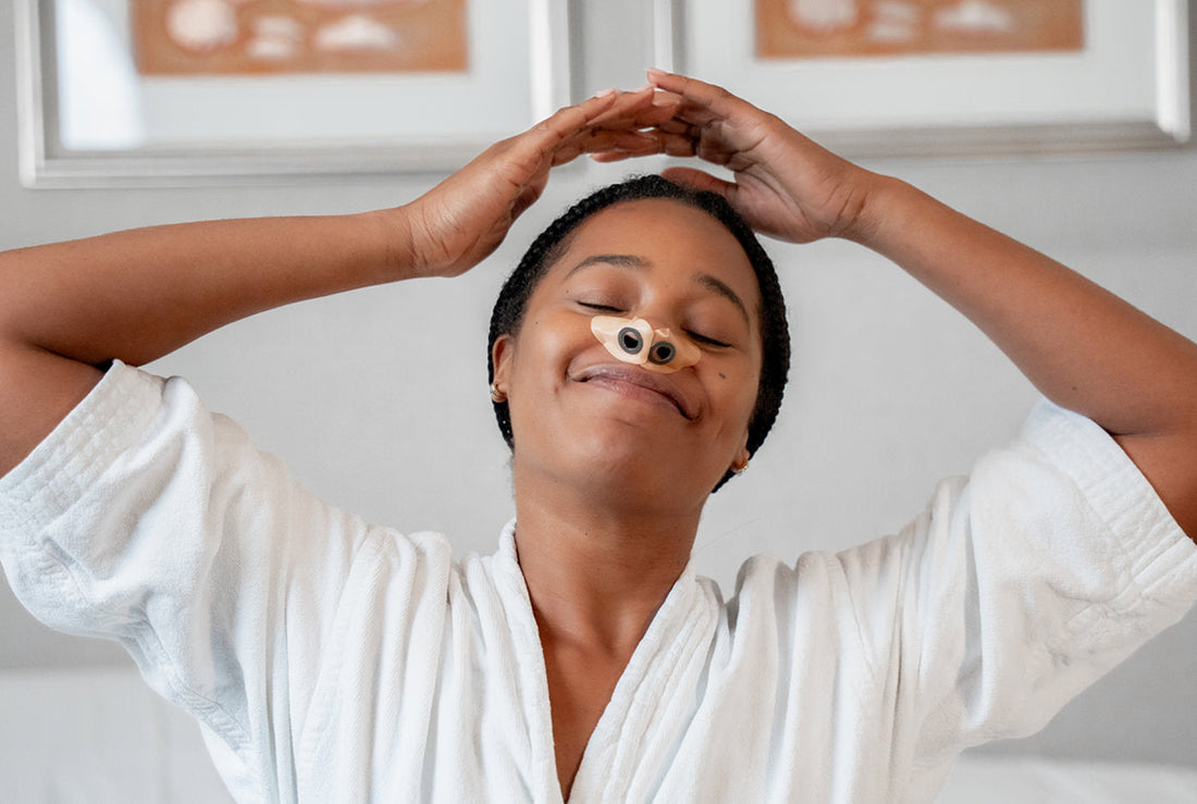 Person wearing a CPAP nasal mask smiles with eyes closed and hands resting on their head, appearing relaxed and comfortable during sleep therapy.